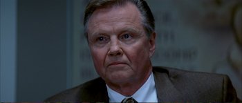 Movie still from “The Rainmaker” (1997), directed by Francis Ford Coppola – An older man in a suit and tie looking at the camera; Close Up shot, Low angle