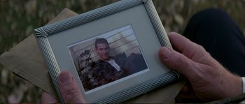 Movie still from “The Rainmaker” (1997), directed by Francis Ford Coppola – A person holding a picture of a man in a suit; Close Up shot, Over the shoulder angle