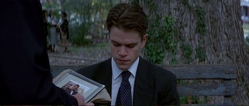 Movie still from “The Rainmaker” (1997), directed by Francis Ford Coppola – A man in a suit and tie reading a book; Close Up shot, Over the shoulder angle
