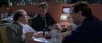 Movie still from “The Rainmaker” (1997), directed by Francis Ford Coppola – A group of people sitting at a table with plates of food; Medium shot, Over the shoulder angle