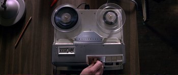 Movie still from “The Rainmaker” (1997), directed by Francis Ford Coppola – A person is playing a tape recorder on a wooden table; Extreme Close Up shot, Overhead angle