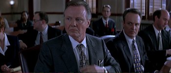 Movie still from “The Rainmaker” (1997), directed by Francis Ford Coppola – An older man wearing a suit and tie holding a pen in his hand; Close Up shot, Low angle