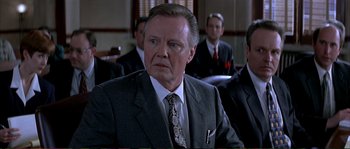 Movie still from “The Rainmaker” (1997), directed by Francis Ford Coppola – An older man wearing a suit and tie in front of a group of men; Close Up shot, Over the shoulder angle