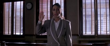 Movie still from “The Rainmaker” (1997), directed by Francis Ford Coppola – A woman in a gray suit is holding up her hand; Medium shot, High angle