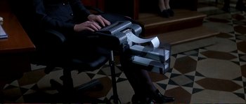 Movie still from “The Rainmaker” (1997), directed by Francis Ford Coppola – A person sitting in a chair using a computer; Medium shot, High angle