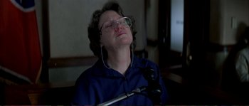 Movie still from “The Rainmaker” (1997), directed by Francis Ford Coppola – An older woman with glasses is sitting in a chair; Close Up shot, Low angle