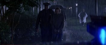 Movie still from “The Rainmaker” (1997), directed by Francis Ford Coppola – A man and a woman walking in the rain with an umbrella; Wide shot, Low angle