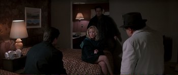 Movie still from “The Rainmaker” (1997), directed by Francis Ford Coppola – A woman sitting on top of a bed next to two men; Medium shot, Over the shoulder angle