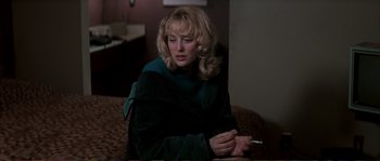 Movie still from “The Rainmaker” (1997), directed by Francis Ford Coppola – A woman smoking a cigarette while sitting on a bed; Close Up shot, High angle