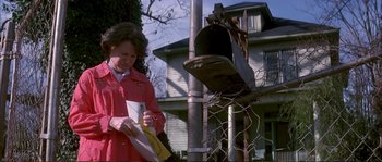 Movie still from “The Rainmaker” (1997), directed by Francis Ford Coppola – A woman standing next to a pole with a mailbox; Medium shot, Low angle