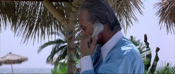 Movie still from “The Rainmaker” (1997), directed by Francis Ford Coppola – An older man talking on a cell phone while standing under a palm tree; Close Up shot, Low angle