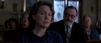 Movie still from “The Rainmaker” (1997), directed by Francis Ford Coppola – A woman sitting next to a man in a room; Close Up shot, Over the shoulder angle