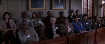 Movie still from “The Rainmaker” (1997), directed by Francis Ford Coppola – A group of people sitting in a row in a courtroom; Medium shot, High angle