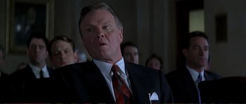 Movie still from “The Rainmaker” (1997), directed by Francis Ford Coppola – An older man in a suit and tie looking at the camera; Close Up shot, Low angle
