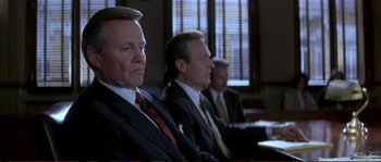 Movie still from “The Rainmaker” (1997), directed by Francis Ford Coppola – A group of men in suits and ties sitting in a room; Close Up shot, Over the shoulder angle