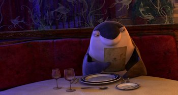 Movie still from “Shark Tale” (2004), directed by Vicky Jenson – An animated penguin sitting at a dinner table; Medium shot, High angle