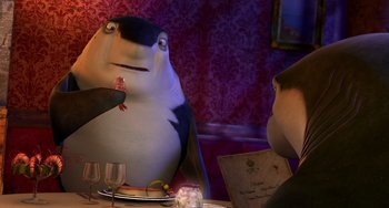 Movie still from “Shark Tale” (2004), directed by Vicky Jenson – A person sitting at a table with a fish in front of him; Medium shot, Over the shoulder angle