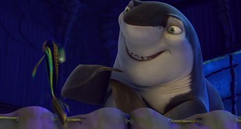 Movie still from “Shark Tale” (2004), directed by Vicky Jenson – A cartoon shark with a fish in its mouth; Medium shot, Low angle
