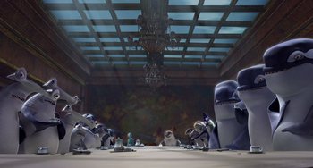 Movie still from “Shark Tale” (2004), directed by Vicky Jenson – A group of people sitting around a table in front of a chandelier; Wide shot, Low angle