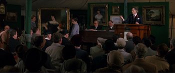 Movie still from “The Remains of the Day” (1993), directed by James Ivory – A group of people sitting in a room with a piano; Wide shot, High angle