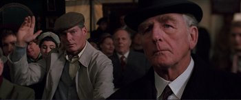 Movie still from “The Remains of the Day” (1993), directed by James Ivory – A group of men in suits and hats in front of a crowd; Close Up shot, Low angle