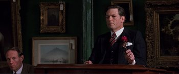 Movie still from “The Remains of the Day” (1993), directed by James Ivory – A man in a suit and tie holding a violin; Medium shot, Over the shoulder angle