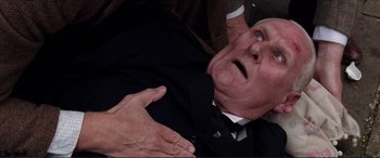 Movie still from “The Remains of the Day” (1993), directed by James Ivory – An older man in a suit and tie holding another older man; Close Up shot, Overhead angle
