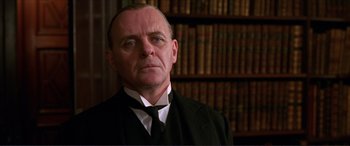 Movie still from “The Remains of the Day” (1993), directed by James Ivory – An older man wearing a suit and tie in front of a book shelf; Close Up shot, Low angle