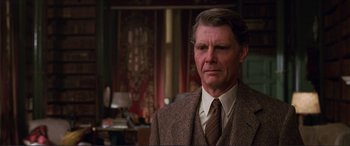 Movie still from “The Remains of the Day” (1993), directed by James Ivory – An older man wearing a suit and tie in a room; Close Up shot, Over the shoulder angle