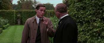 Movie still from “The Remains of the Day” (1993), directed by James Ivory – A man in a trench coat talking to another man in a suit; Close Up shot, Over the shoulder angle