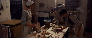 Movie still from “The Remains of the Day” (1993), directed by James Ivory – Three people in a kitchen preparing food on top of a wooden table; Medium shot, High angle