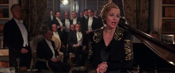 Movie still from “The Remains of the Day” (1993), directed by James Ivory – A woman is singing in front of a group of men; Medium shot, High angle