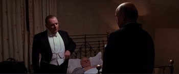 Movie still from “The Remains of the Day” (1993), directed by James Ivory – A man in a suit and tie next to two other men; Medium shot, Over the shoulder angle