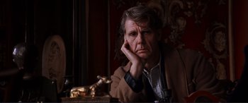 Movie still from “The Remains of the Day” (1993), directed by James Ivory – A man sitting at a table with his hand under his chin; Close Up shot, Over the shoulder angle