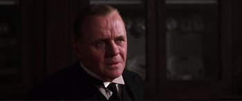 Movie still from “The Remains of the Day” (1993), directed by James Ivory – A person wearing a suit and tie; Close Up shot, Over the shoulder angle