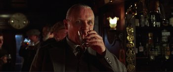 Movie still from “The Remains of the Day” (1993), directed by James Ivory – An older man is drinking a glass of wine; Close Up shot, Over the shoulder angle