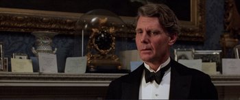 Movie still from “The Remains of the Day” (1993), directed by James Ivory – A man in a tuxedo standing in front of a clock; Close Up shot, Low angle