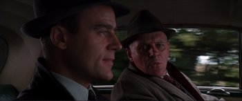Movie still from “The Remains of the Day” (1993), directed by James Ivory – A man in a suit and a man in a hat in the back of a car; Close Up shot, Over the shoulder angle