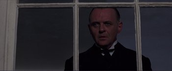Movie still from “The Remains of the Day” (1993), directed by James Ivory – A man wearing a suit and bow tie looking out of a window; Close Up shot, Over the shoulder angle