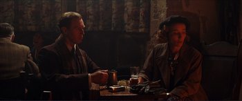 Movie still from “The Remains of the Day” (1993), directed by James Ivory – A man and woman sitting at a table with a drink; Medium shot, Over the shoulder angle