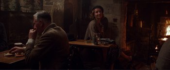 Movie still from “The Remains of the Day” (1993), directed by James Ivory – A woman sitting at a wooden table in front of a brick wall; Medium shot, Over the shoulder angle