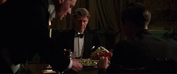 Movie still from “The Remains of the Day” (1993), directed by James Ivory – A man sitting at a dinner table looking at a plate of food; Medium shot, Over the shoulder angle