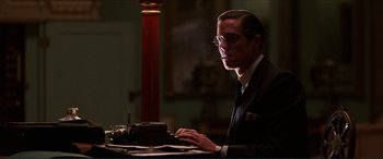 Movie still from “The Remains of the Day” (1993), directed by James Ivory – A man sitting at a table typing on a typewriter; Medium shot, Low angle