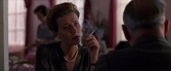 Movie still from “The Remains of the Day” (1993), directed by James Ivory – A woman smoking a cigarette while sitting at a table; Close Up shot, Low angle