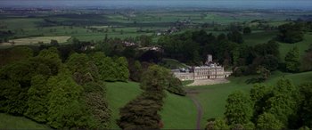 Movie still from “The Remains of the Day” (1993), directed by James Ivory – An aerial view of a large mansion in the middle of a lush green field; Extreme Wide shot, High angle