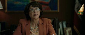 Movie still from “The Report” (2019), directed by Scott Z. Burns – An older woman wearing glasses and a brown jacket; Close Up shot, Low angle