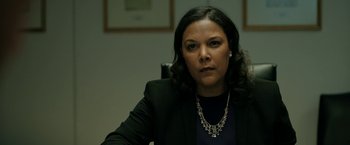 Movie still from “The Report” (2019), directed by Scott Z. Burns – A woman sitting in a chair wearing a black jacket; Close Up shot, Over the shoulder angle