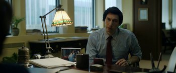 Movie still from “The Report” (2019), directed by Scott Z. Burns – A man sitting at a table in front of a lamp; Medium shot, Over the shoulder angle