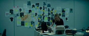 Movie still from “The Report” (2019), directed by Scott Z. Burns – A woman sitting at a desk in front of a bunch of papers; Extreme Wide shot, High angle