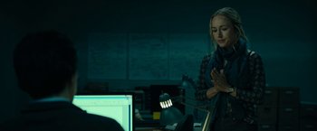 Movie still from “The Report” (2019), directed by Scott Z. Burns – A woman standing in front of a computer monitor; Medium shot, Over the shoulder angle